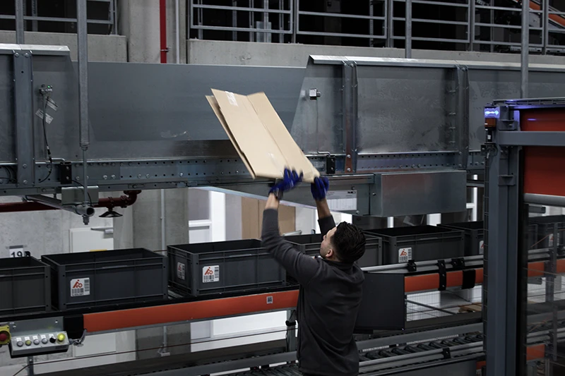 Employee packing shipments with the PaperJet paper cushioning system at Hoffmann Group