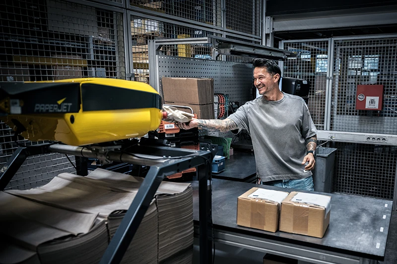 Employee operating the PaperJet paper cushioning system at a Linde Material Handling packaging station